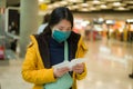 Asian woman flying in covid19 times - lifestyle portrait of young beautiful and tired Chinese girl in face mask waiting on airport Royalty Free Stock Photo