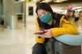 Asian woman flying in covid19 times - lifestyle portrait of young beautiful and tired Korean girl in face mask waiting on airport Royalty Free Stock Photo