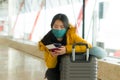 Asian woman flying in covid19 times - lifestyle portrait of young beautiful and tired Korean girl in face mask waiting on airport Royalty Free Stock Photo