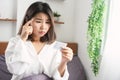 Asian woman forget to take birth control pill sitting in bed with worry face