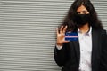 Asian woman at formal wear and black protect face mask hold Howland and Baker Islands flag at hand against gray background.