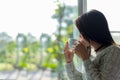 Asian woman fresh morning drinking coffee and looking out of the window on sunny day