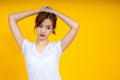 Asian woman gathering her hair over yellow background