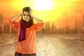 Asian woman getting a headache because of the heatwave on the city with glowing sun background