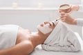 Asian woman getting skin treatment at spa, beautician applying clay face mask Royalty Free Stock Photo