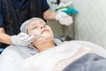 Asian woman getting treatment applying facial cream mask at spa therapist clinic. Royalty Free Stock Photo