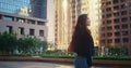 Asian woman going street back view. Lady look around high urban buildings.