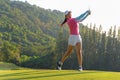 Asian woman golf player doing golf swing tee off on the green evening time, she presumably does exercise. Royalty Free Stock Photo