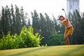 Asian woman golf player hitting chips golf ball to the hole on the green with golf club in the sunny day, copy space. Royalty Free Stock Photo