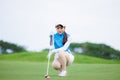 Asian woman golfer sit check line for putting golf ball on green grass Royalty Free Stock Photo