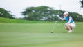 Asian woman golfer sit check line for putting golf ball on green grass Royalty Free Stock Photo