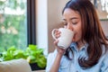 An Asian woman in a good mood is drinking coffee happily. Women feel relaxed with the aroma of a drink in the house or cafe. Food Royalty Free Stock Photo