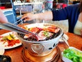 Asian woman grill raw sliced beef and pork on the hot stainless steel stove with smoke Royalty Free Stock Photo