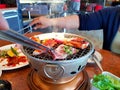 Asian woman grilled raw sliced beef and pork on the hot stainless steel stove with smoke Royalty Free Stock Photo