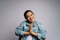 Asian woman guilty holding hands in prayer standing isolated over white background