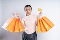 Asian woman guilty worried nervous holding more shopping bags and credit card isolated over background