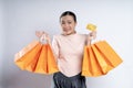 Asian woman guilty worried nervous holding more shopping bags and credit card isolated over background