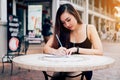 Asian woman hand checking shopping list on desk at outside outlet mall. Royalty Free Stock Photo