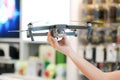 Asian woman hand hold the Gray Drone in blur electronic store