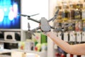 Asian woman hand hold the Gray Drone in blur electronic store