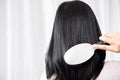 Asian woman hand holding comb brushing her beautiful long black and shiny hair Royalty Free Stock Photo