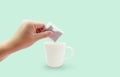 Asian woman hand holding dry tea bag of herb for making tea in white ceramic cup or mug on light blue background with copy space Royalty Free Stock Photo