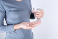 Asian woman hand holding painkillers and water glass on white background, Health and medical concept