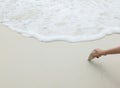 Asian Woman Hand Holding White Sea Stone at The Corner on The Clean and Empty White Sand Beach with Sea Wave as Frame Royalty Free Stock Photo