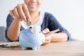 Asian woman hand is putting a coin in a piggy bank and banknote on the table at home, Investment business and retirement. finance Royalty Free Stock Photo