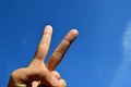 Asian woman hand showing victory or peace against blue sky Royalty Free Stock Photo