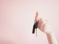 Asian woman hanging car key by beauty finger with pink pastel ba