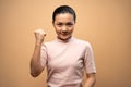 Asian woman happy confident standing make a winning gesture isolated on beige background