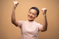 Asian woman happy confident standing make a winning gesture isolated on beige background