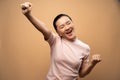 Asian woman happy confident standing make a winning gesture isolated on beige background