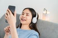 Asian woman of happy smiling are listening to music from white headphones and using hands touch smartphone. Royalty Free Stock Photo