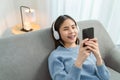 Asian woman of happy smiling are listening to music from white headphones and using hands touch smartphone. Royalty Free Stock Photo