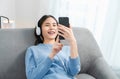 Asian woman of happy smiling are listening to music from white headphones and using hands touch smartphone on vacation. Royalty Free Stock Photo