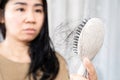 Asian woman have a problem with hair loss after brushing  holding a comb with hair fall Royalty Free Stock Photo