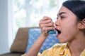 Asian woman having an asthma attack using an asthma inhaler at home