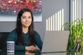 Asian woman having a business call in headphones at a desk, working on laptop in home office Royalty Free Stock Photo