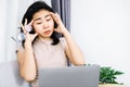 Asian woman having headache and tired her eyes from overworked on computer screen hand holding eyeglasses