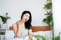 Asian woman having neck pain, sore muscle, shoulder and back ache sitting in bed after wakeup in morning Royalty Free Stock Photo