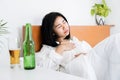 Asian woman having problems with GERD , acid reflux, and heartburn with gastritis from drinking beer before sleeping in bed Royalty Free Stock Photo