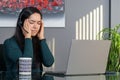 Asian woman having a stressful business call in headphones at a desk in home office Royalty Free Stock Photo