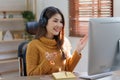 Asian woman having video call on her computer at home. listening to online lecture, taking notes, online study at home Royalty Free Stock Photo