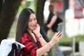 Asian woman having video call with her friends on smart while sitting outdoor in the city. Royalty Free Stock Photo