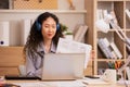 Asian woman in headphones using laptop computer having video call sitting in modern office or home, learning language. Freelancer Royalty Free Stock Photo