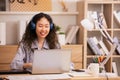 Asian woman in headphones using laptop computer having video call sitting in modern office or home, learning language. Freelancer Royalty Free Stock Photo