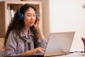 Asian woman in headphones using laptop computer having video call sitting in modern office or home, learning language. Freelancer Royalty Free Stock Photo