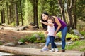 Asian Woman with her little daughter in the woods near the river standing on a log